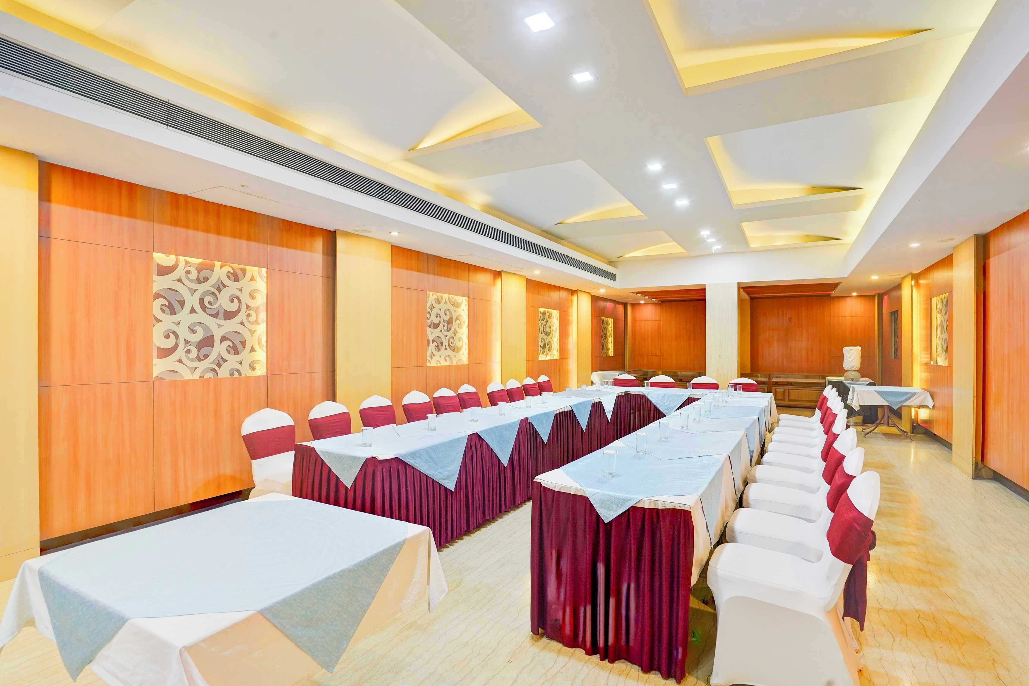 A conference room with long tables, red and white chairs, and wooden paneling.