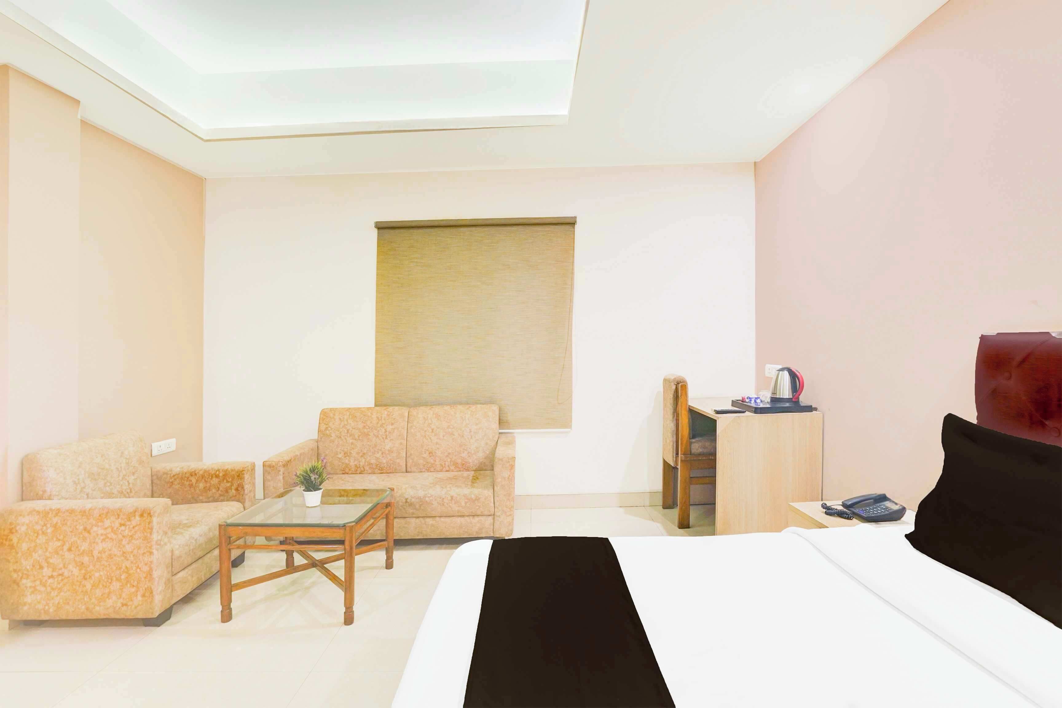 A hotel room with a bed, two sofas, a coffee table, a desk, and a window.