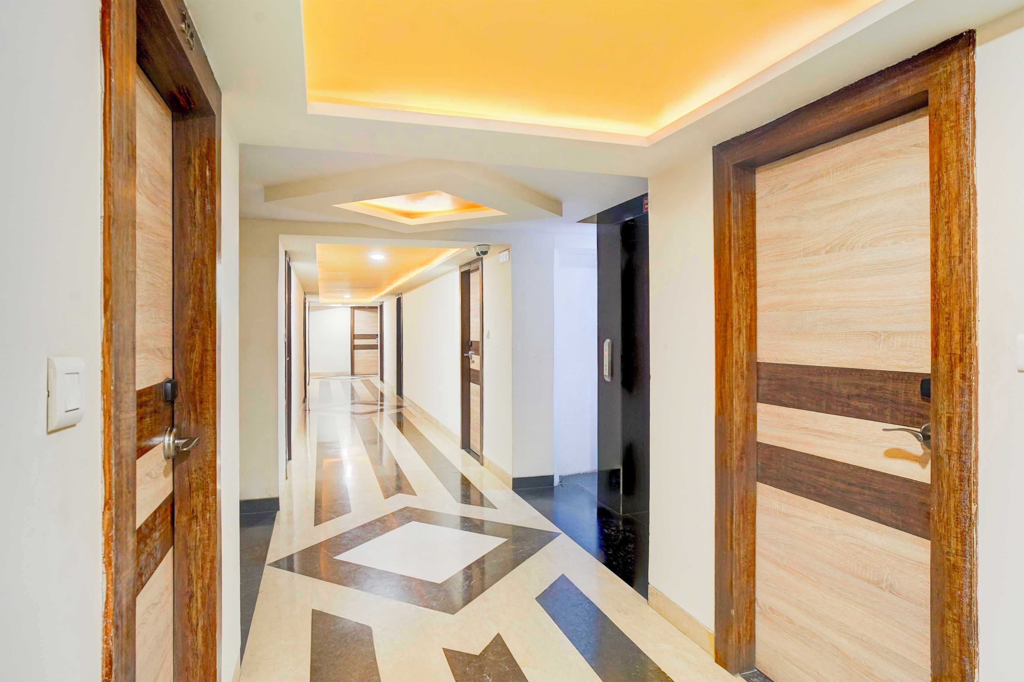 A hallway with wooden doors, a geometric patterned floor, and recessed ceiling lighting.