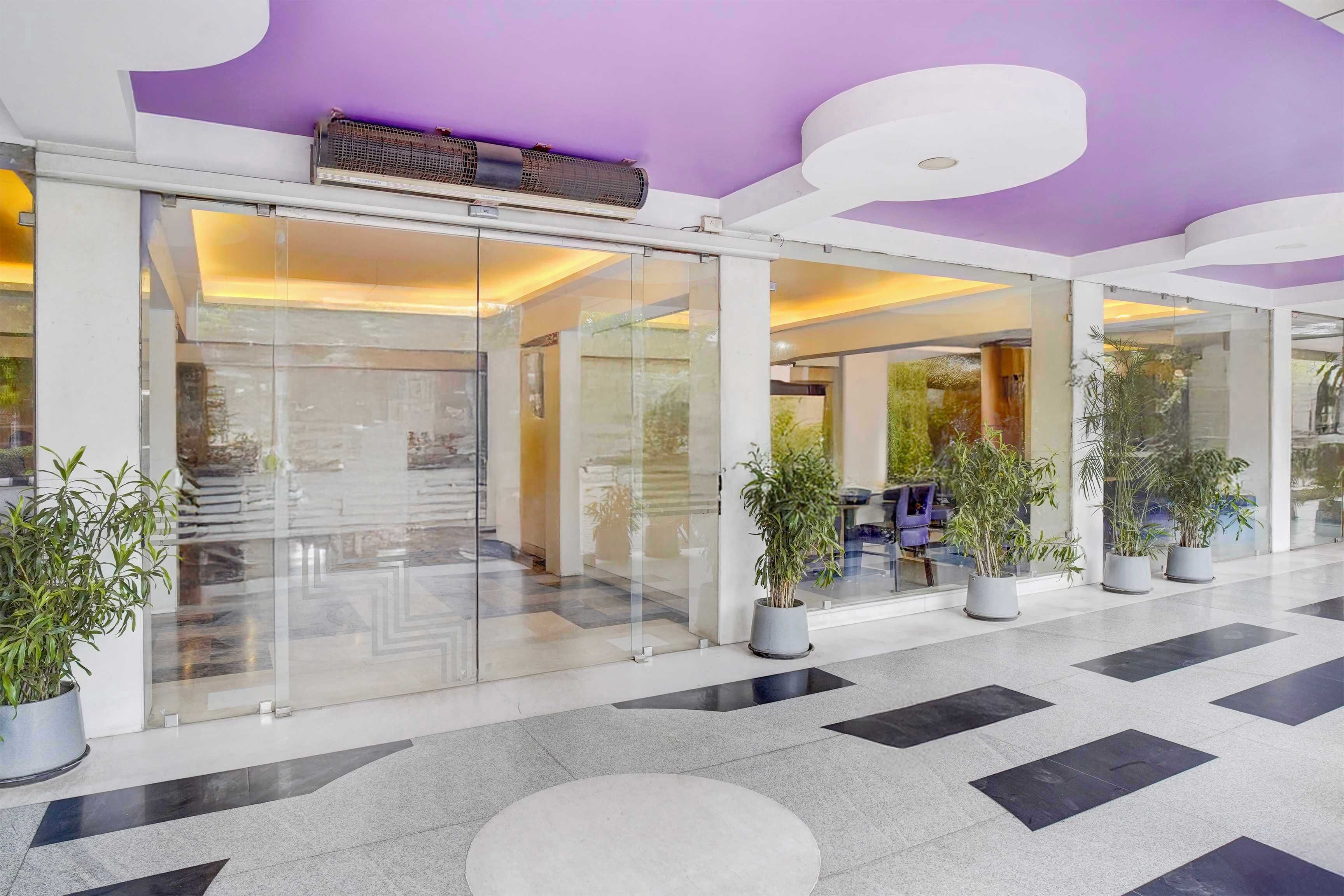 Eine moderne Lobby mit Glastüren, Blumentöpfen und einem gemusterten Boden.