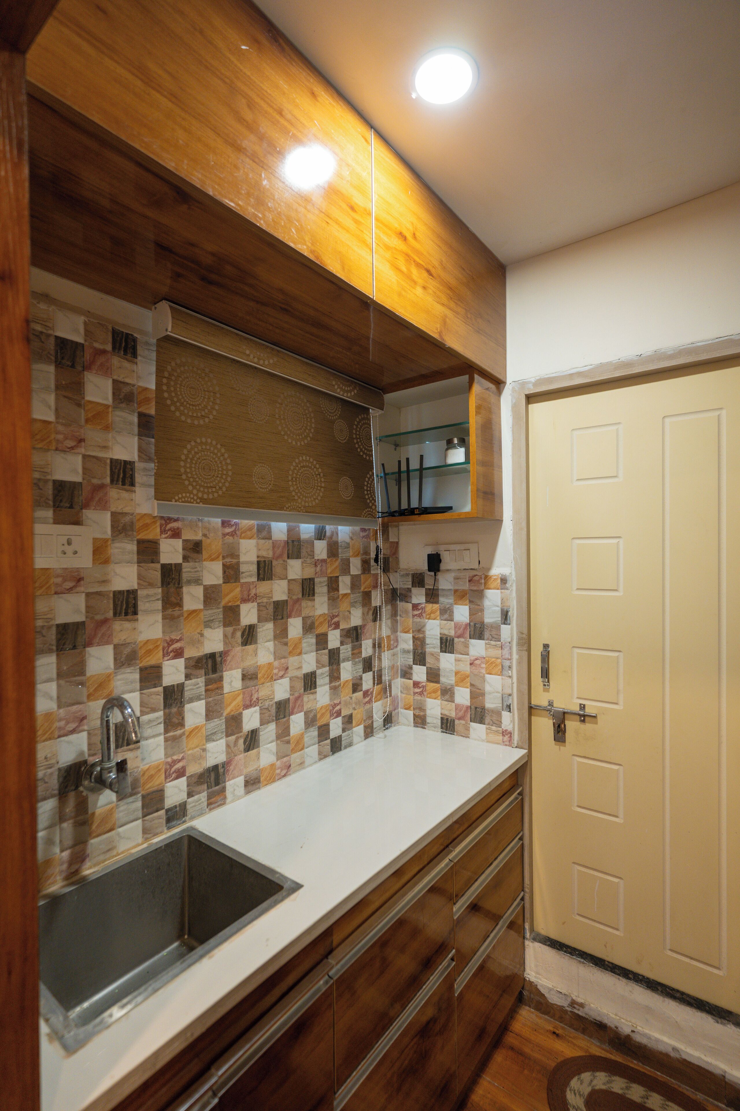 A kitchen with a tiled backsplash, wooden cabinets, a sink, and a door.