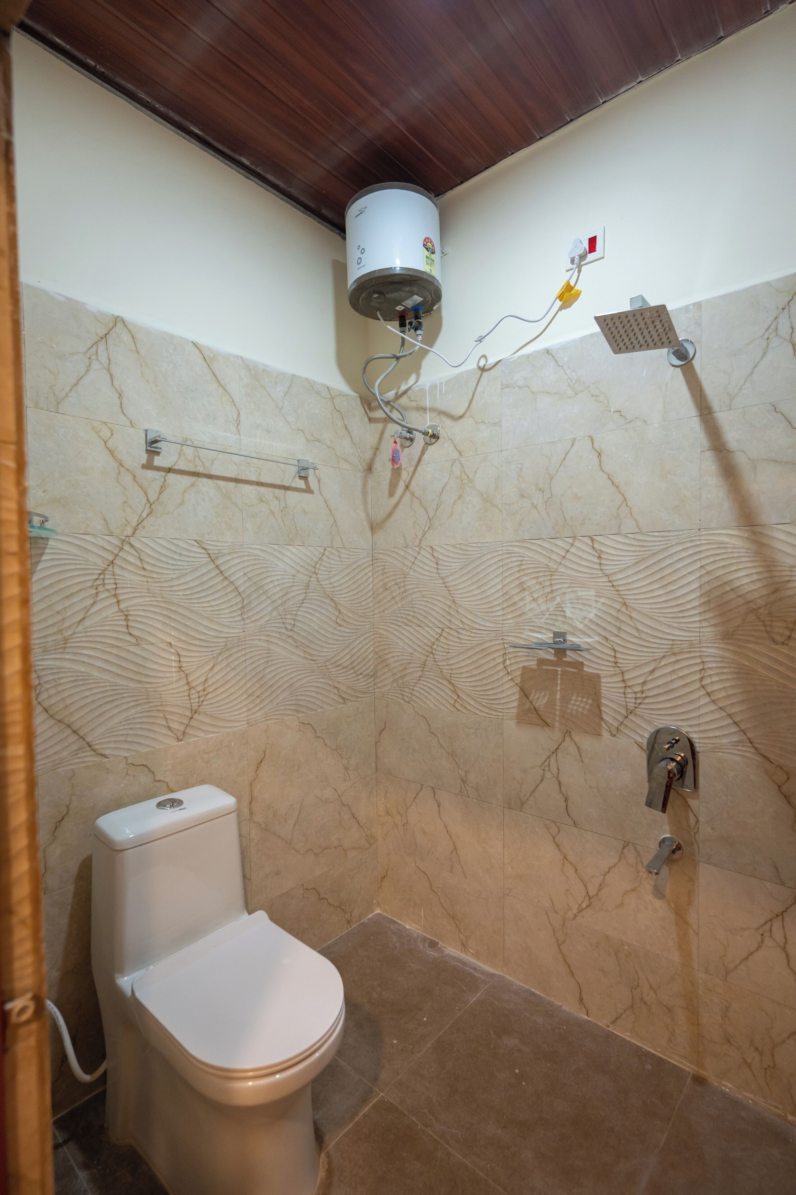 A bathroom with a toilet, a shower, and a marble-patterned wall.