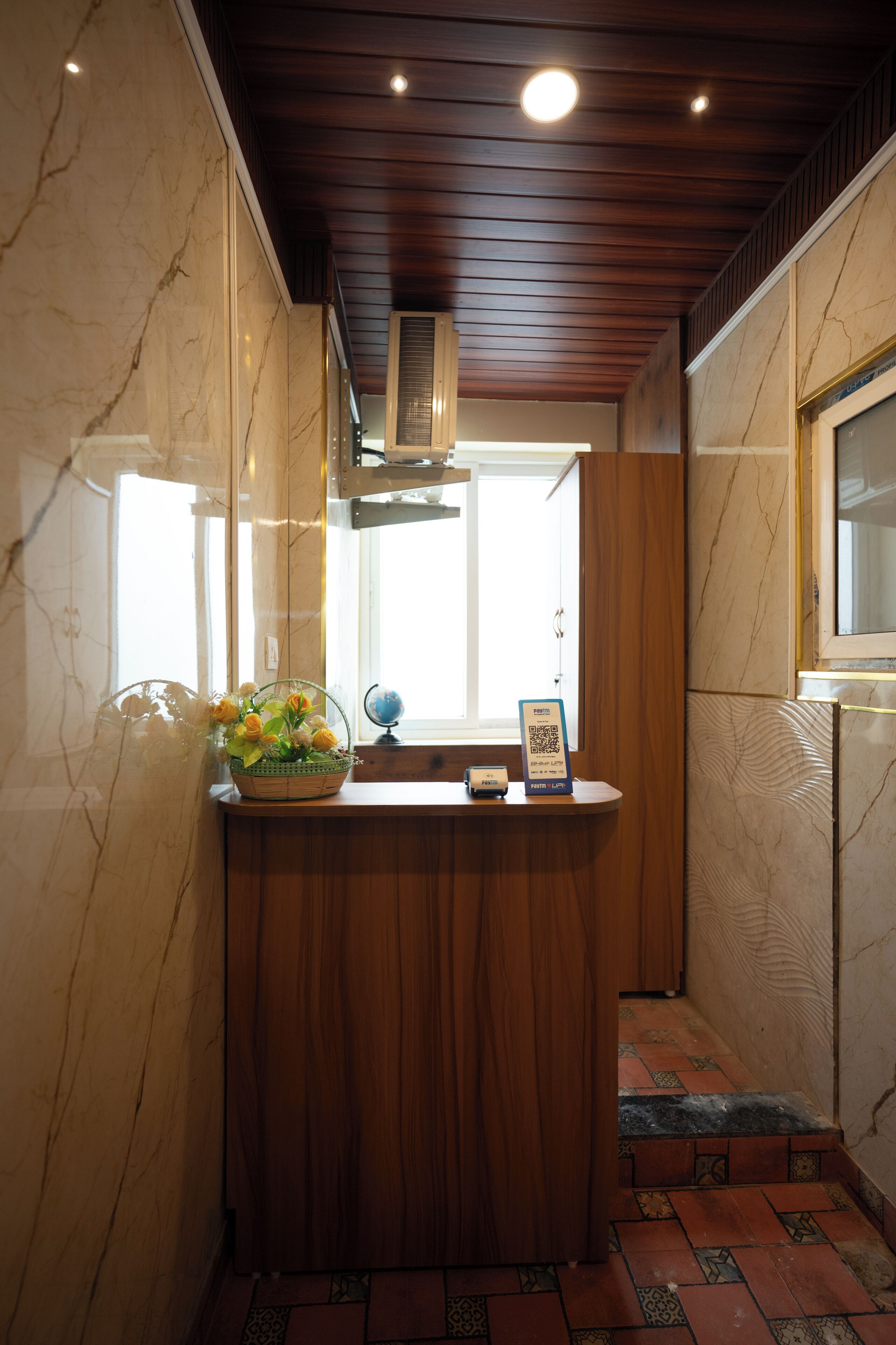 Un mostrador de recepción con una pared de mármol, paneles de madera y piso de baldosas.
