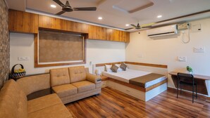 A compact room with a sofa, a bed, a desk, and a ceiling fan. - Anand's Abode By Yellow Bells (Hyderabad)