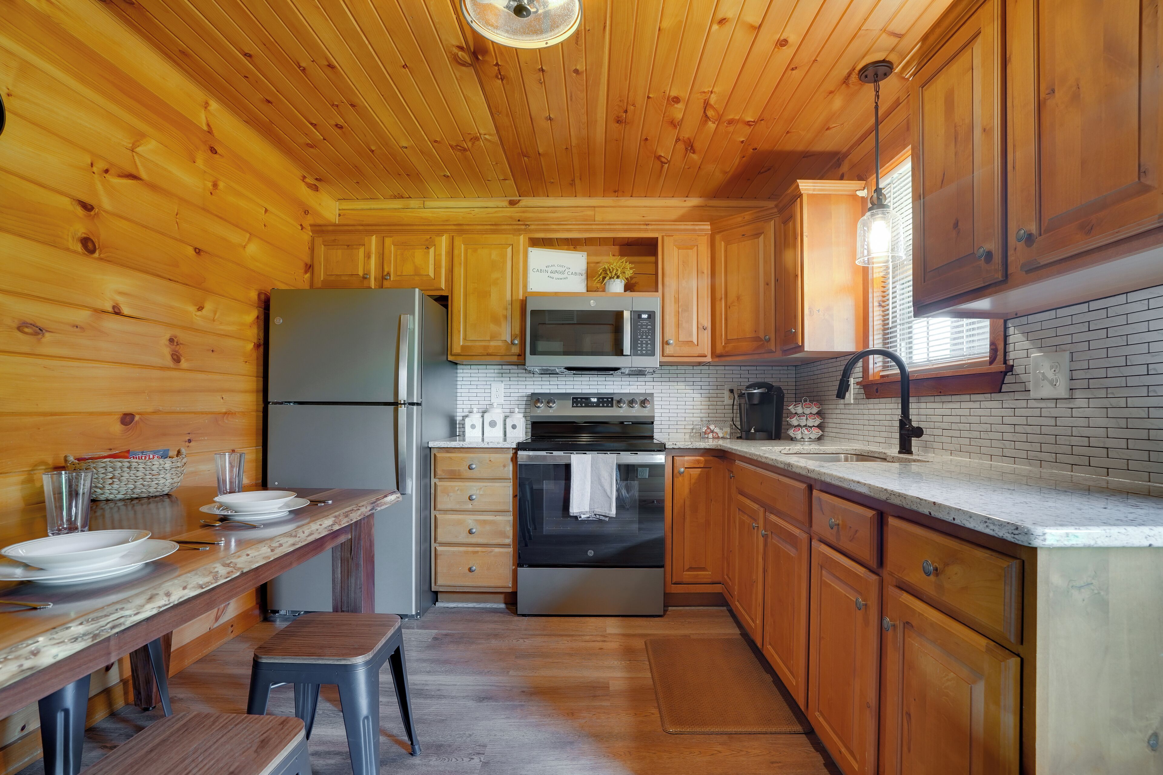 A wooden-paneled kitchen with a refrigerator, microwave, oven, and wooden cabinets.