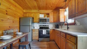 A wooden-paneled kitchen with a refrigerator, microwave, oven, and wooden cabinets.