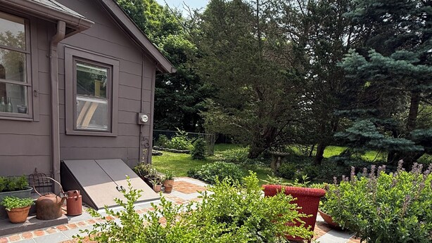 A house with a brick patio, potted plants, and a small garden area.