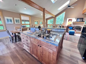A spacious kitchen with a central island, wooden cabinets, and a large window providing natural light.