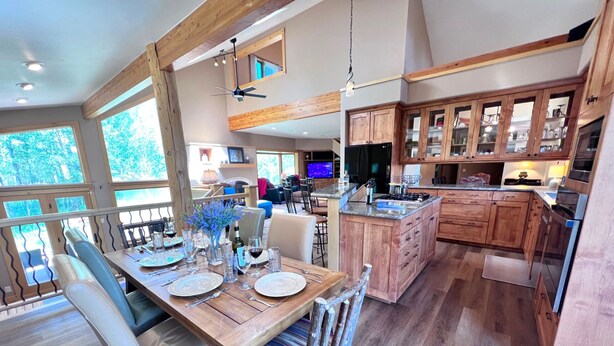 A spacious kitchen with wooden cabinets, a dining area with a wooden table set for four, and a large island with a sink.