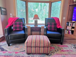 A room with two black leather chairs, a small ottoman, a lamp, and a bookshelf. - Aspen Hollow Lodge w/ Hot Tub + Fire Pit (Frisco)