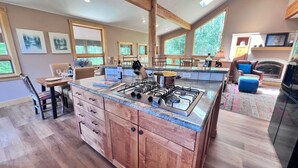 A spacious kitchen with a central island, wooden cabinets, and a large window providing natural light.