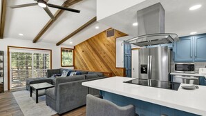 A modern kitchen with a central island, stainless steel appliances, and blue cabinets.