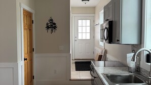 A modern kitchen with a marble countertop, stainless steel sink, and grey cabinets.
