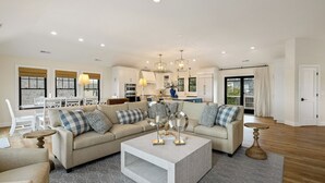 Ett rymligt vardagsrum med en beige soffa, ett soffbord och en matplats med ett vitt bord och stolar.
