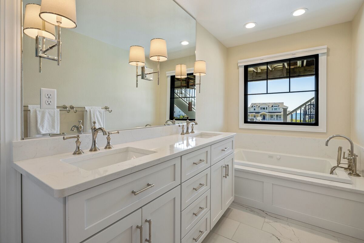 A modern bathroom with two sinks, a large mirror, and a bathtub.
