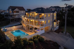 A multi-story house with a pool, outdoor seating, and a flag. - Here & Now - Beautifully Remodeled 5 BR Semi-Oceanfront Home w/Pool (Duck)