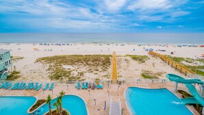 Un complejo turístico en la playa con piscina, tobogán y sombrillas.