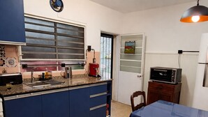 A kitchen with blue cabinets, a coffee maker, and a dining area with a table and chairs. - Private Room in a Shared House with a Balcony and Air Conditioning Near the San Isidro Racetrack (Martínez)