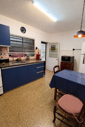 A kitchen with blue cabinets, a coffee maker, and a dining area with a table and chairs.