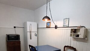 Une cuisine compacte comprenant une table, des chaises, un réfrigérateur, un four à micro-ondes, un luminaire suspendu et un petit placard.