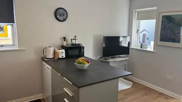 Eine kleine Küche mit Mikrowelle, Toaster und Kaffeemaschine. Ein Flachbildfernseher ist an der Wand befestigt.