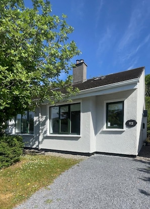 A modern two-story house with a white exterior, large windows, and a chimney. - 112 Clifden Glen Holiday Home (Clifden)