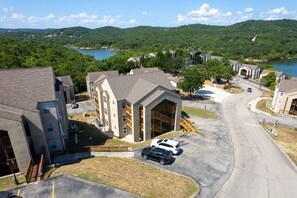 A residential area with a central building featuring a large garage, surrounded by houses and a lake in the background. - New beautiful condo 2-king bedrooms 2-full baths sleeps 6-7 next to SDC (Branson)