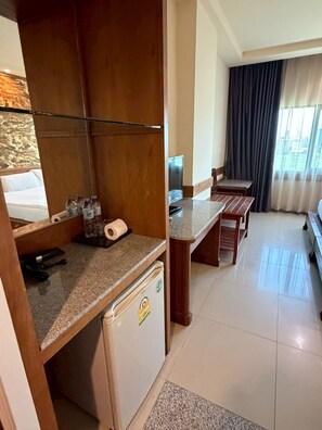 Habitación de hotel con kitchenette, cama, zona de estar y vista a la ciudad.
