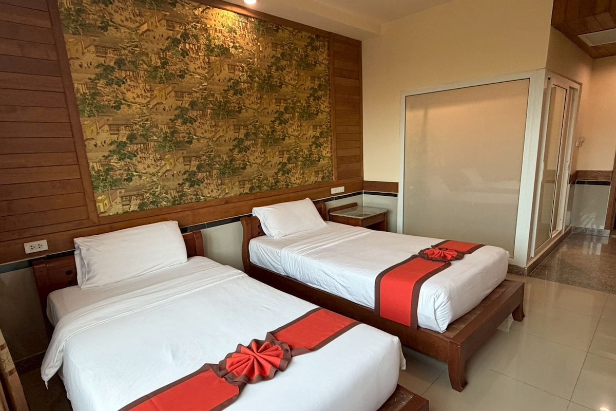 A hotel room with two beds, a wooden headboard, a map on the wall, and a sliding door.