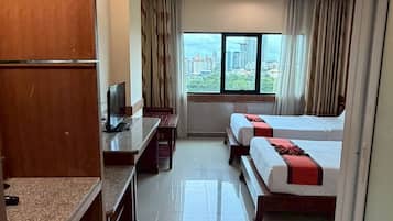 Habitación de hotel con cama, escritorio, televisor y ventana con vista a la ciudad.