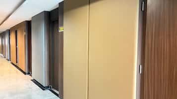 Pasillo de hotel con varias puertas, cada una con un cartel con número.