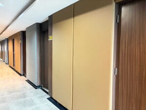 A hotel corridor with multiple doors, each with a number sign above.