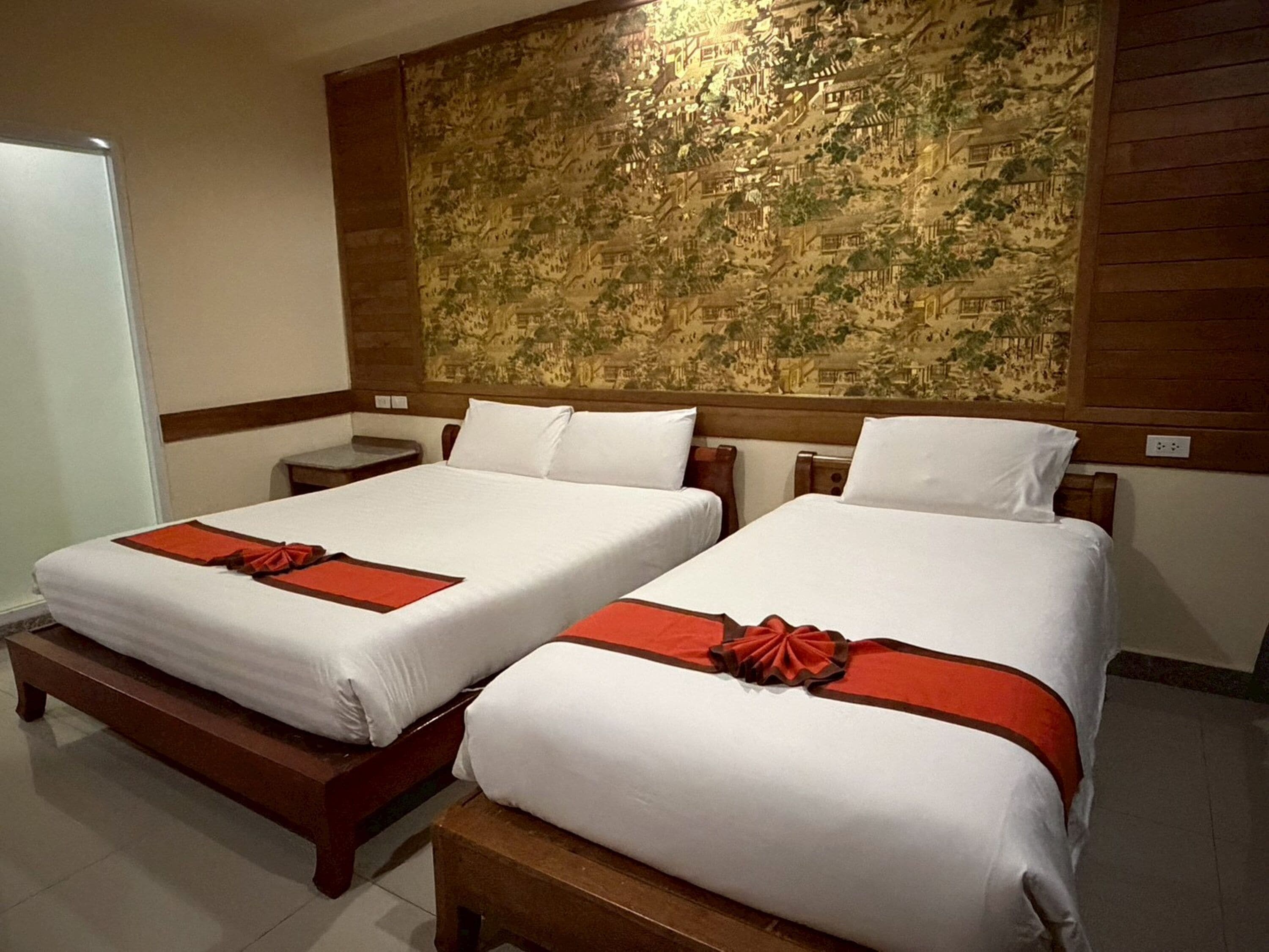 A hotel room with two beds, a large wall tapestry, and a wooden headboard.
