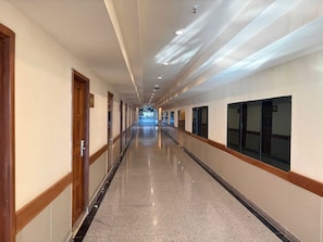 A long, well-lit corridor with doors on one side and windows on the other, leading to a distant area. - Sunday Grand Jomtien Pattaya (Pattaya)