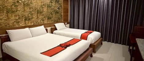 A hotel room with two beds, a large tapestry on the wall, and a view of the city through the window.