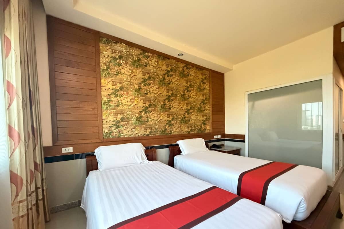 Une chambre d’hôtel avec deux lits, un grand mur décoratif et une porte-fenêtre coulissante.