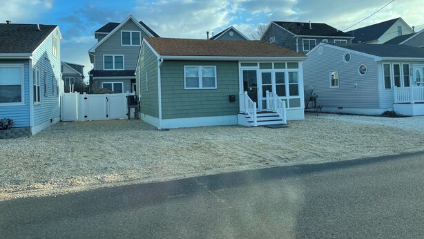 A row of single-story houses with a gravel driveway and a white picket fence.
