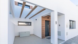 Un bâtiment moderne au design minimaliste, caractérisé par une structure en poutres de bois, un petit banc et une porte portant le numéro « 9 ».
