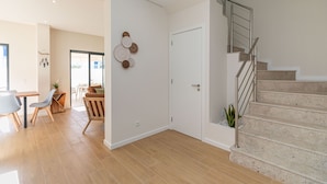 Un vaste espace de vie doté d’un plancher en bois, d’un escalier avec des rampes en métal et d’une porte donnant sur une autre pièce.
