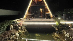 A modern house with a triangular roof, a small patio, and a pond. - Chalet Nordique Balnéo&spa  (Villampuy)