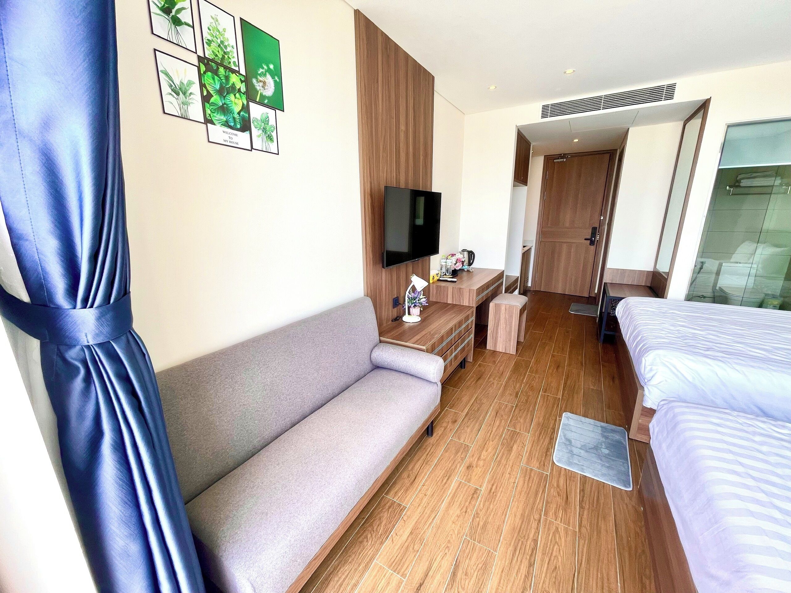 A hotel room with a sofa, a bed, a TV, and a desk.