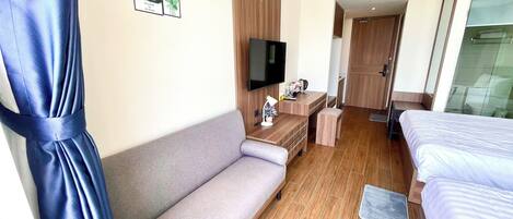 A hotel room with a sofa, a bed, a TV, and a desk.