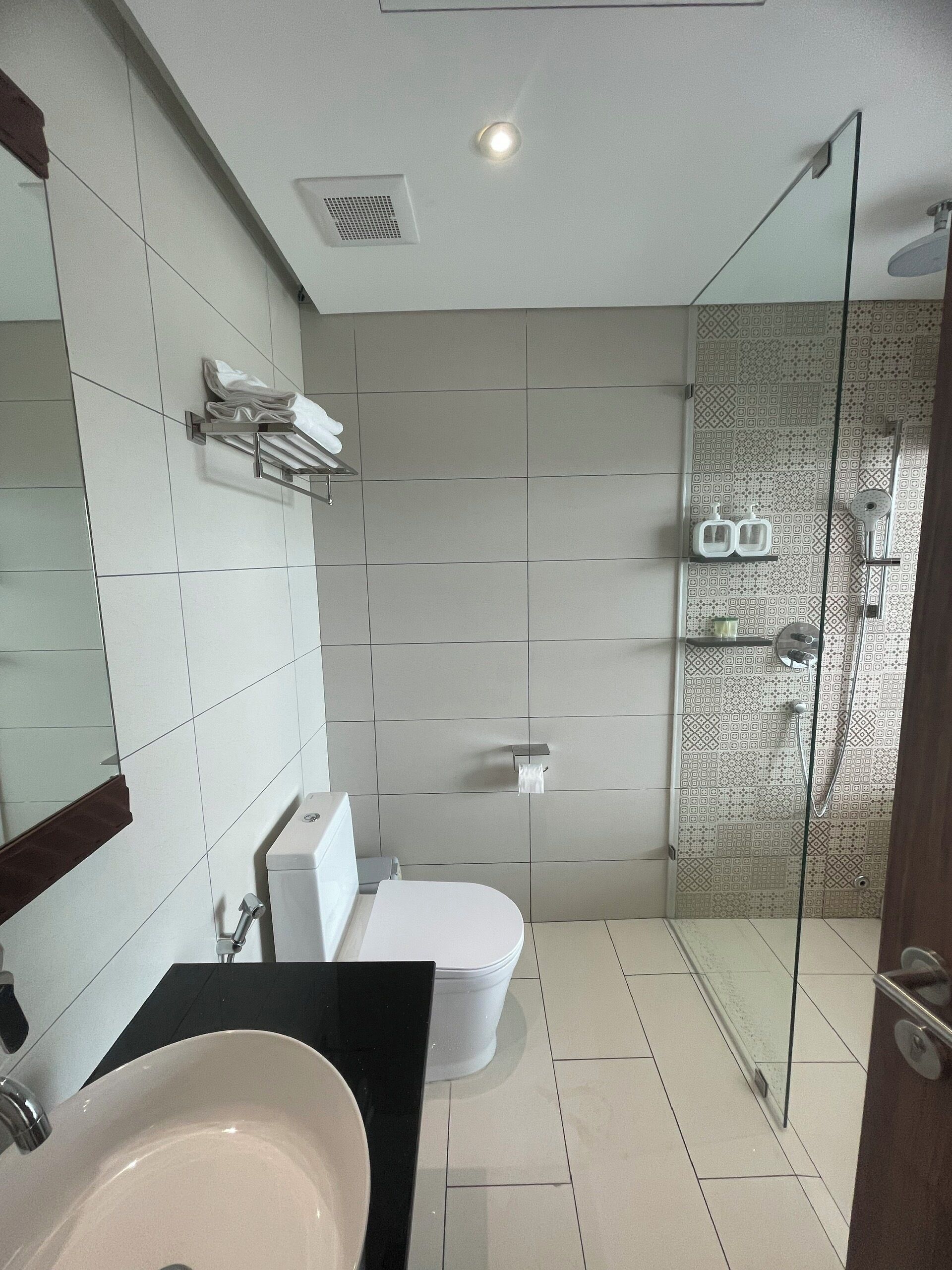 A modern bathroom with a glass-enclosed shower, a white toilet, and a sink with a black countertop.