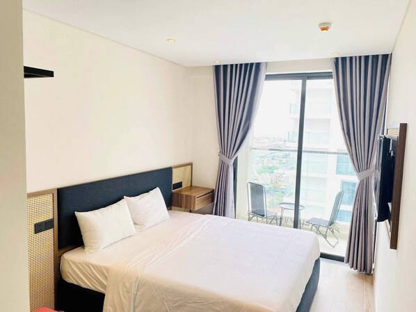 Une chambre d’hôtel avec un grand lit, une petite table, une chaise et un balcon avec vue.