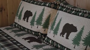 A bed with a plaid blanket and two pillows featuring a bear and tree pattern. - 2-bedroom Sleeping Rooms in fantastic Watertown SD with WiFi, AC (Watertown)