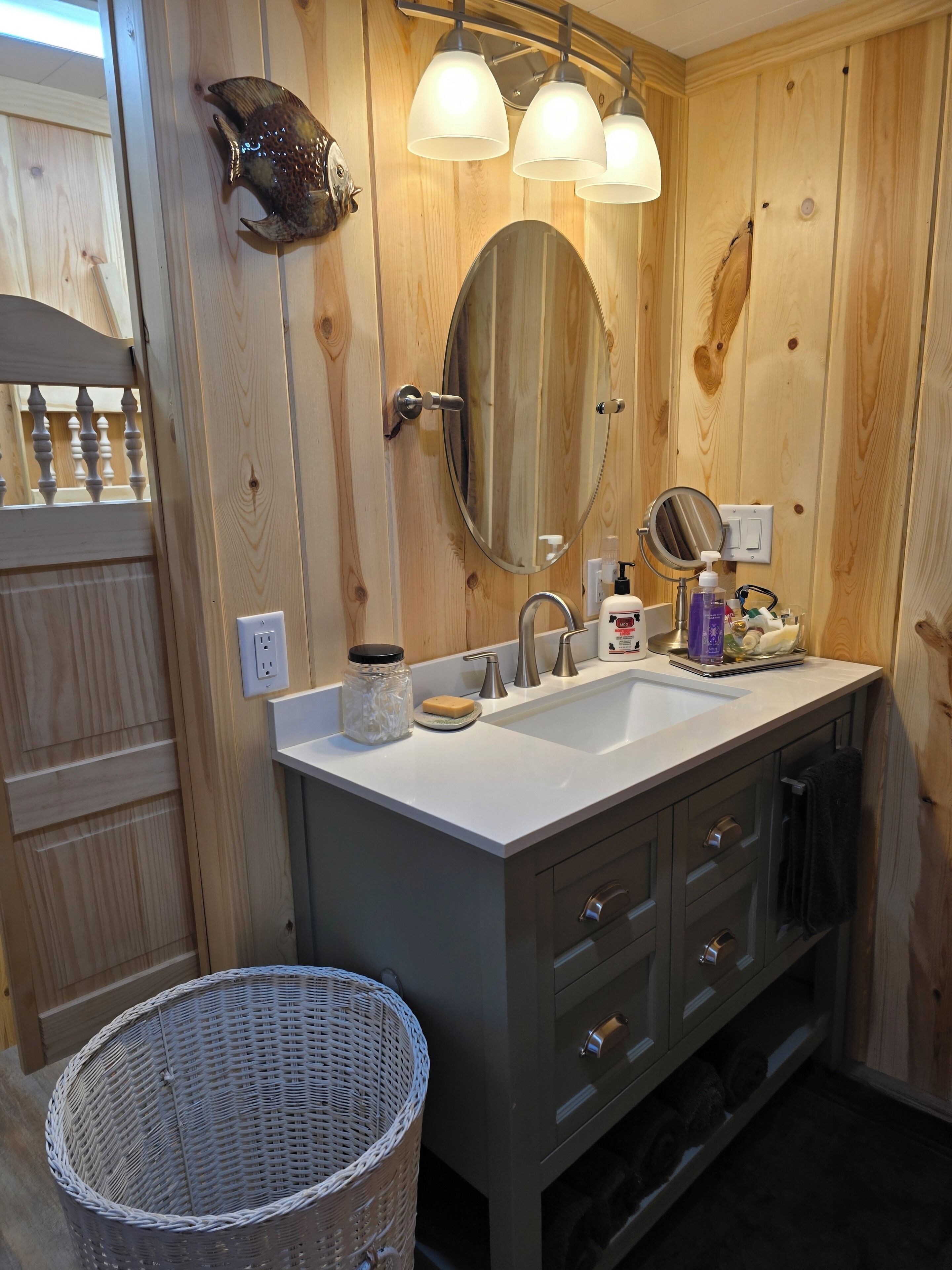 Ein Badezimmer aus Holz mit Waschtisch, Spiegel und Waschbecken.