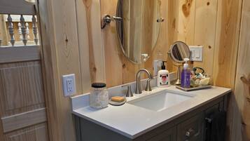 Ein Badezimmer aus Holz mit Waschtisch, Spiegel und Waschbecken.