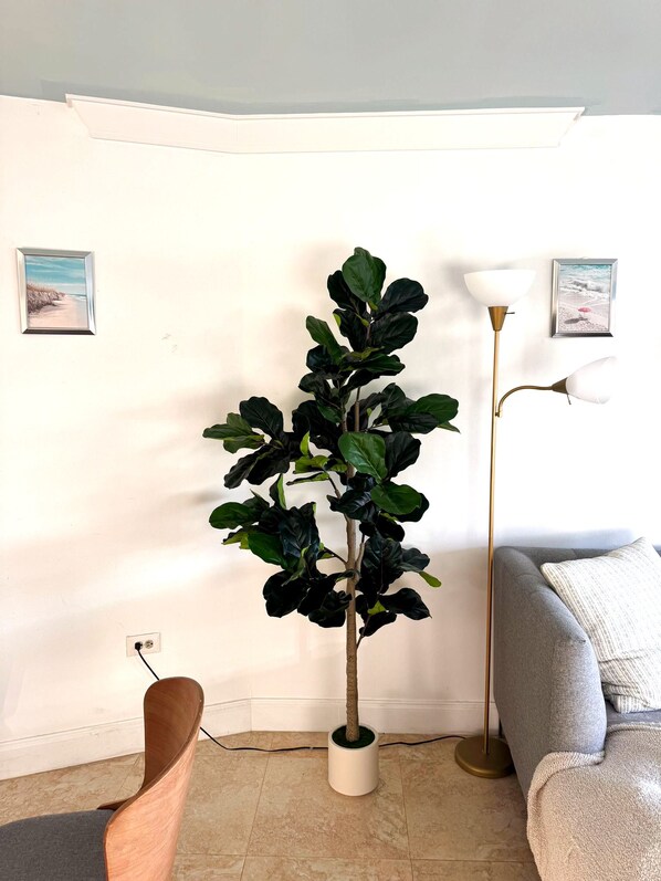 Una habitación con una planta en maceta, una lámpara y un sofá.
