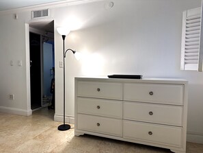 Una habitación con un aparador blanco, una lámpara de pie y una puerta que da a un armario.