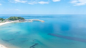 Vista aérea de una zona costera con playa, muelle y un pueblo pequeño.